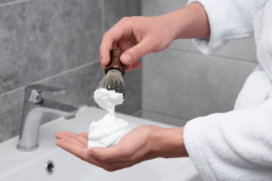 Sử dụng cọ để thoa đều kem hoặc bột cạo râu chuyên dụng trước khi áp dụng cách cạo râu